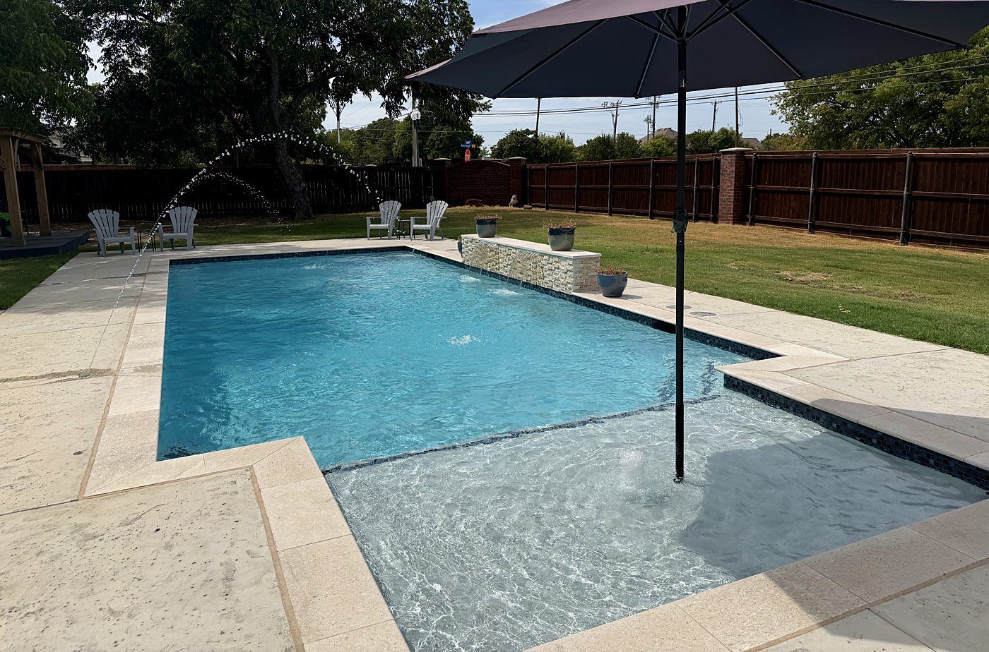 Pool with a tanning ledge, raised feature wall and umbrella sleeve