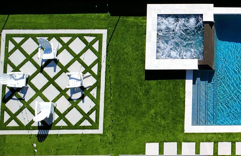 Raised spa beside a turf and paver lounge area