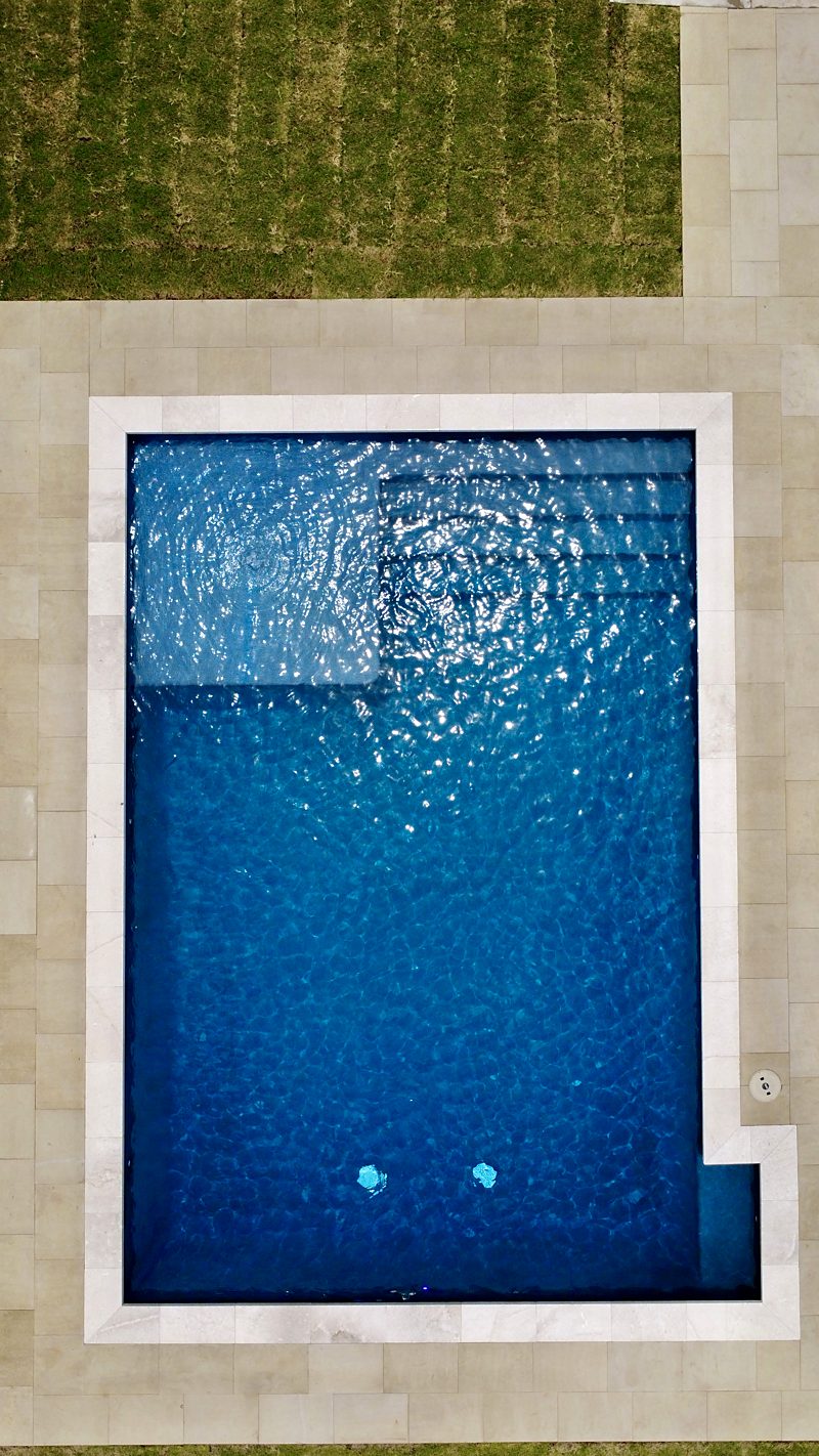 Overhead view of a rectangular pool with bench and steps